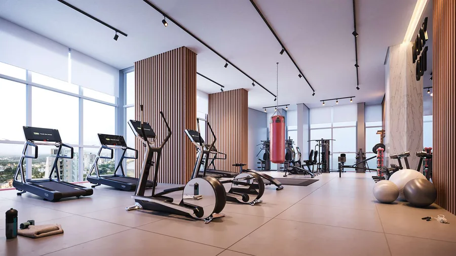 Academia com esteiras e elípticos alinhados diante das janelas, e aparelhos de musculação ao fundo