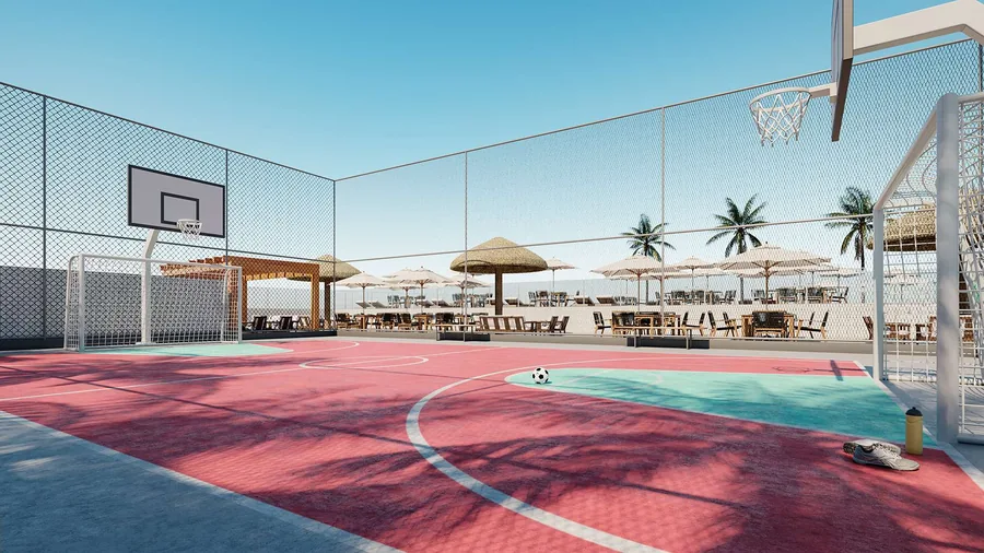 Quadra poliesportiva fechada por tela, com piso vermelho e azul, cestas de basquete e guarda-sóis ao fundo