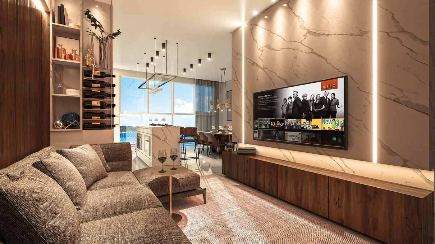Living do apartamento tipo, com sofá amplo, painel de televisão em mármore e adega embutida na marcenaria