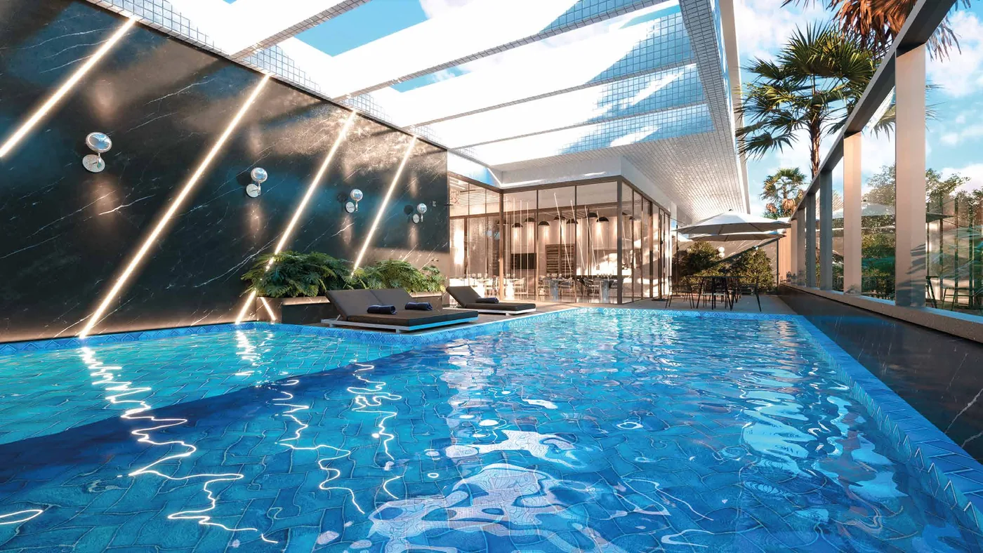 Piscina sob cobertura de vidro, com palmeiras em volta, espreguiçadeiras e o estar envidraçado ao fundo