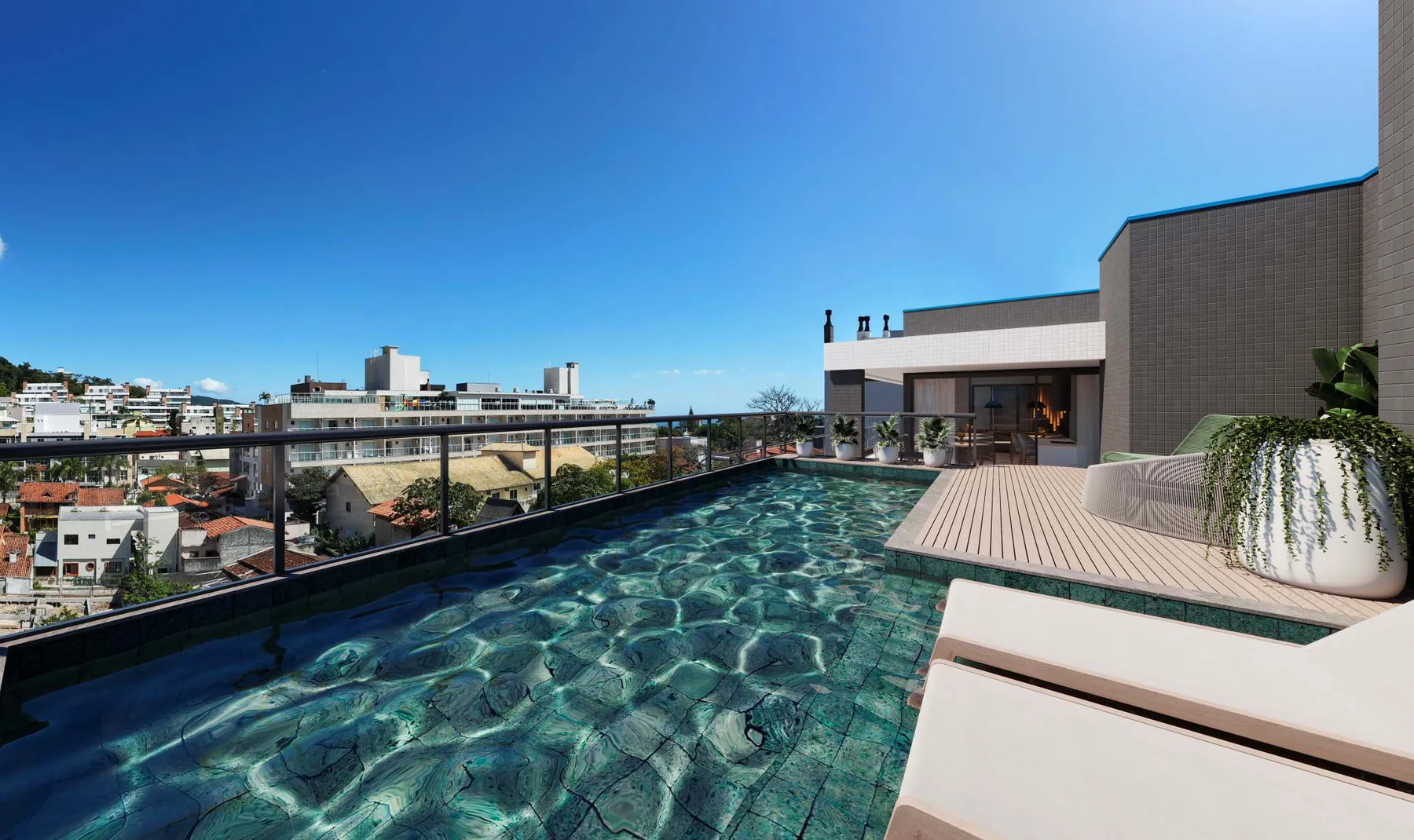 Piscina no rooftop em dia de sol, com a lâmina de água correndo junto à borda, espreguiçadeiras no deck e os telhados do Centro de Bombinhas embaixo