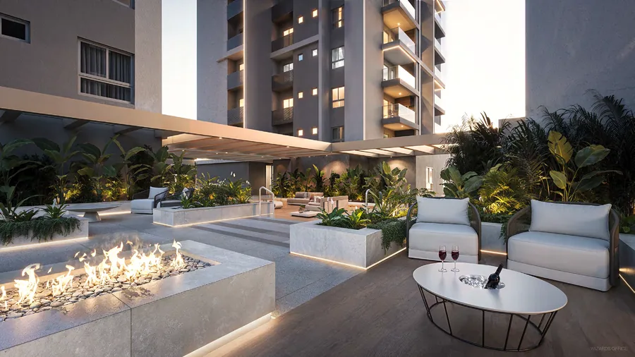 Lounge externo com fireplace corrido aceso, poltronas claras e vegetação alta em volta, sob a varanda do pavimento de lazer