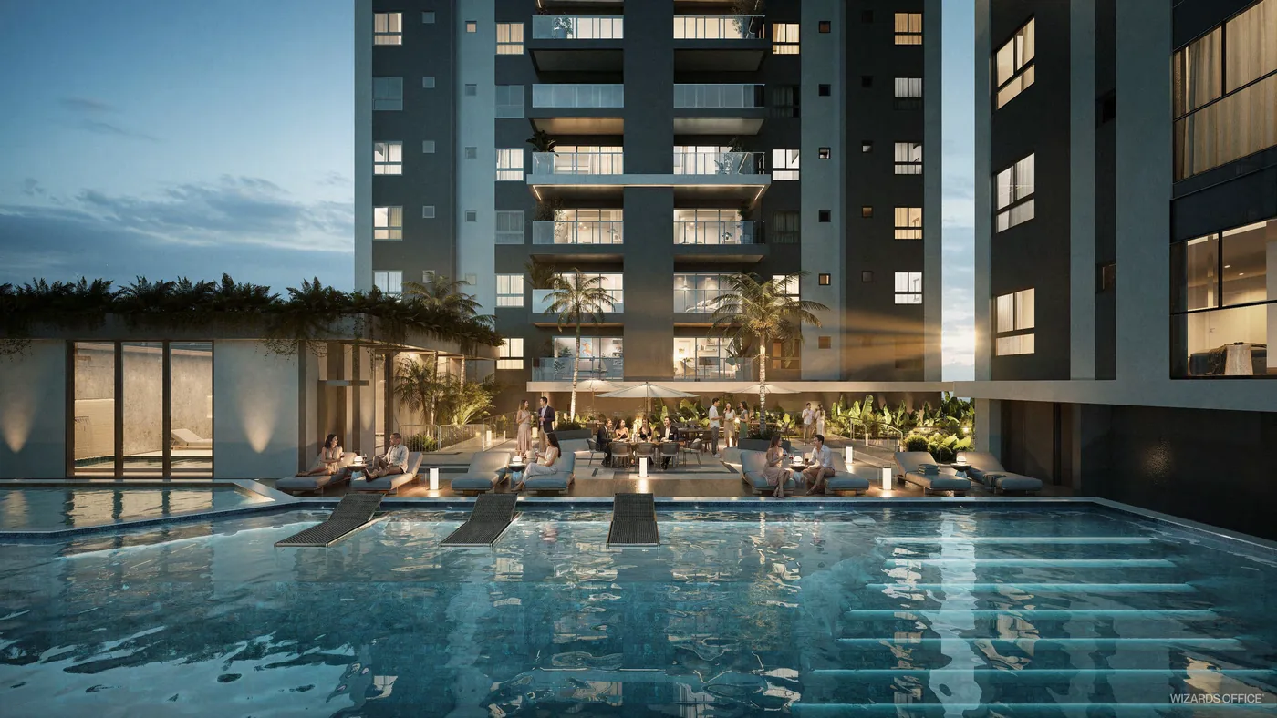 Piscina externa ao anoitecer, com raias iluminadas, deck em volta e as fachadas das torres atrás