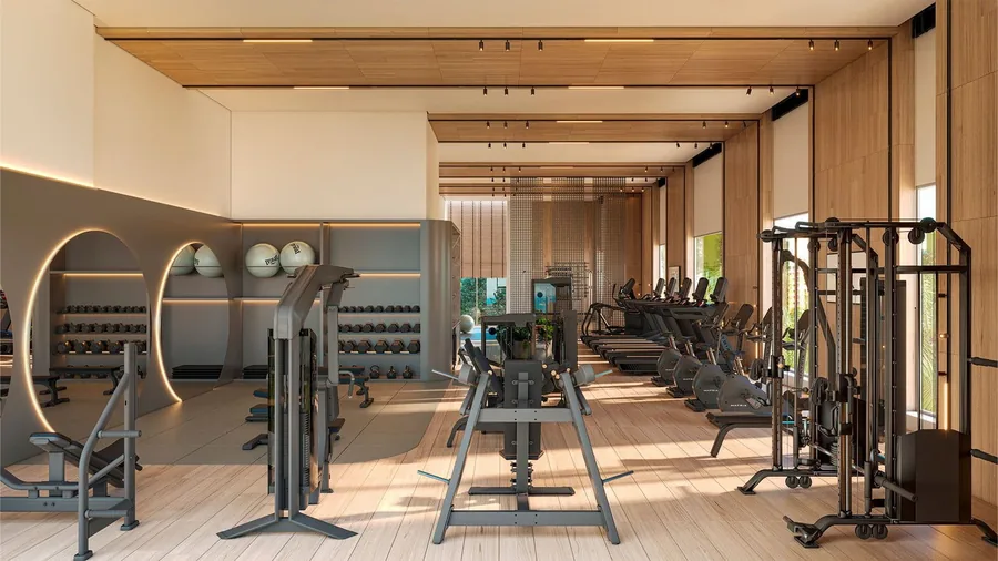 Academia com aparelhos de musculação alinhados e janelas altas para a vegetação