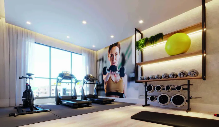 Academia com esteira, bicicleta ergométrica, rack de halteres e bolas de pilates, diante de uma janela alta
