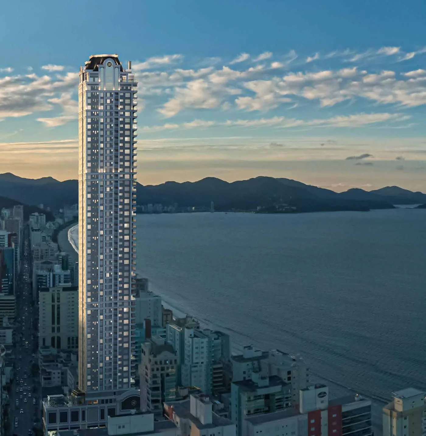 Vista aérea da torre do L'Atelier erguida sobre a orla de Itapema, com a praia e o mar ao lado