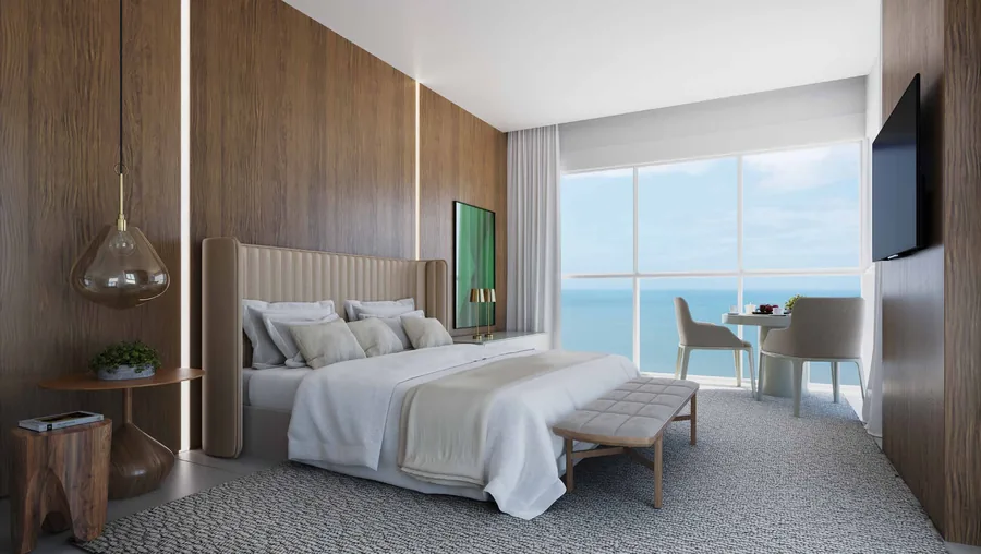 Suíte deluxe da cobertura, com cama de casal, poltrona de leitura e parede de vidro para o mar