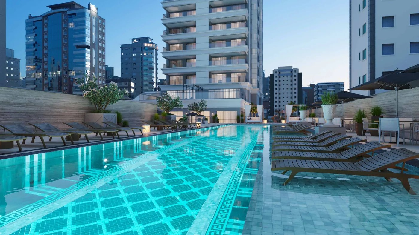Piscina com raia semiolímpica no pavimento de lazer, com espreguiçadeiras alinhadas e os prédios da orla ao fundo