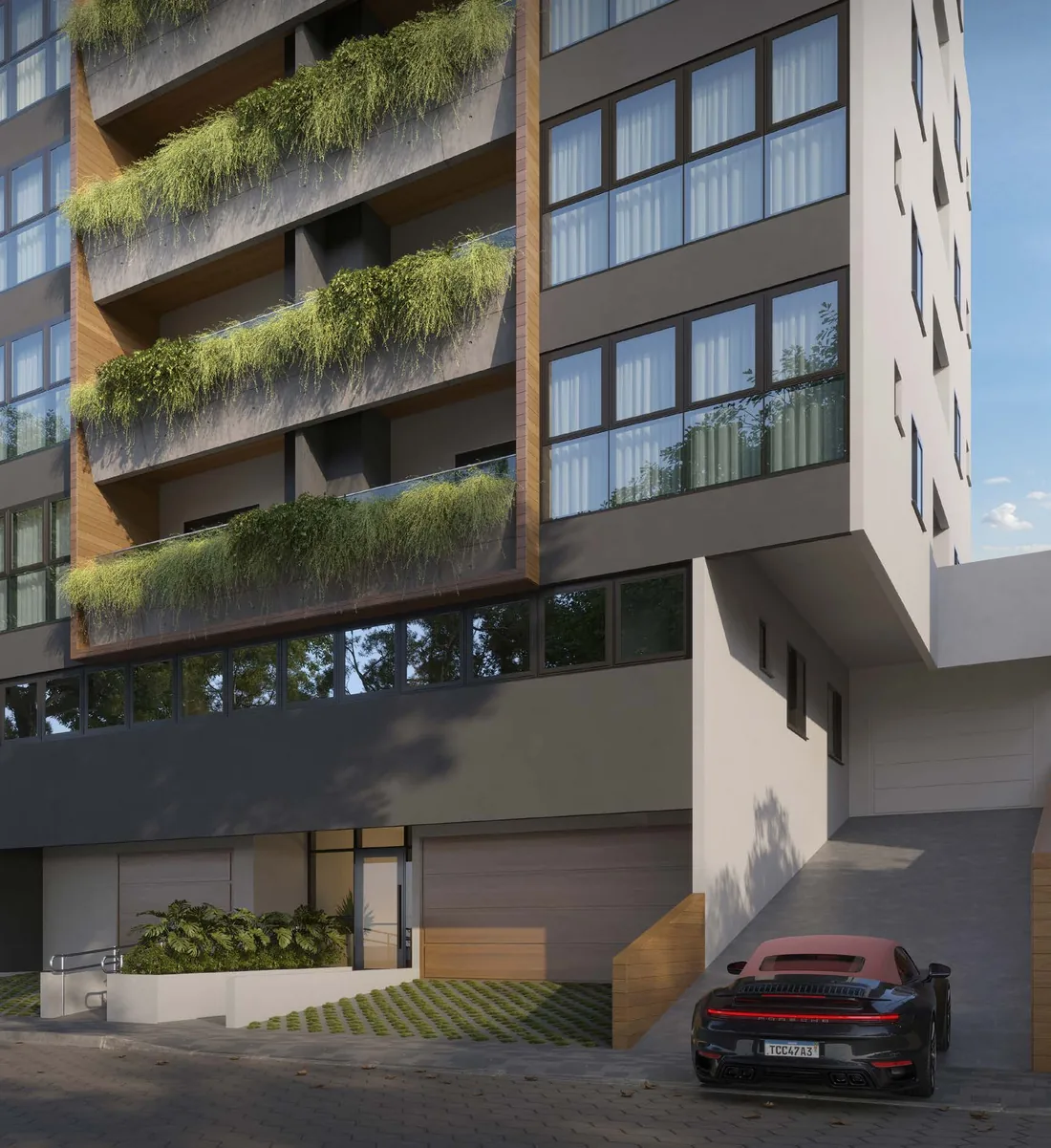 Esquina do Liv Green ao nível da rua, com o acesso de garagem, o embasamento e as sacadas com vegetação acima