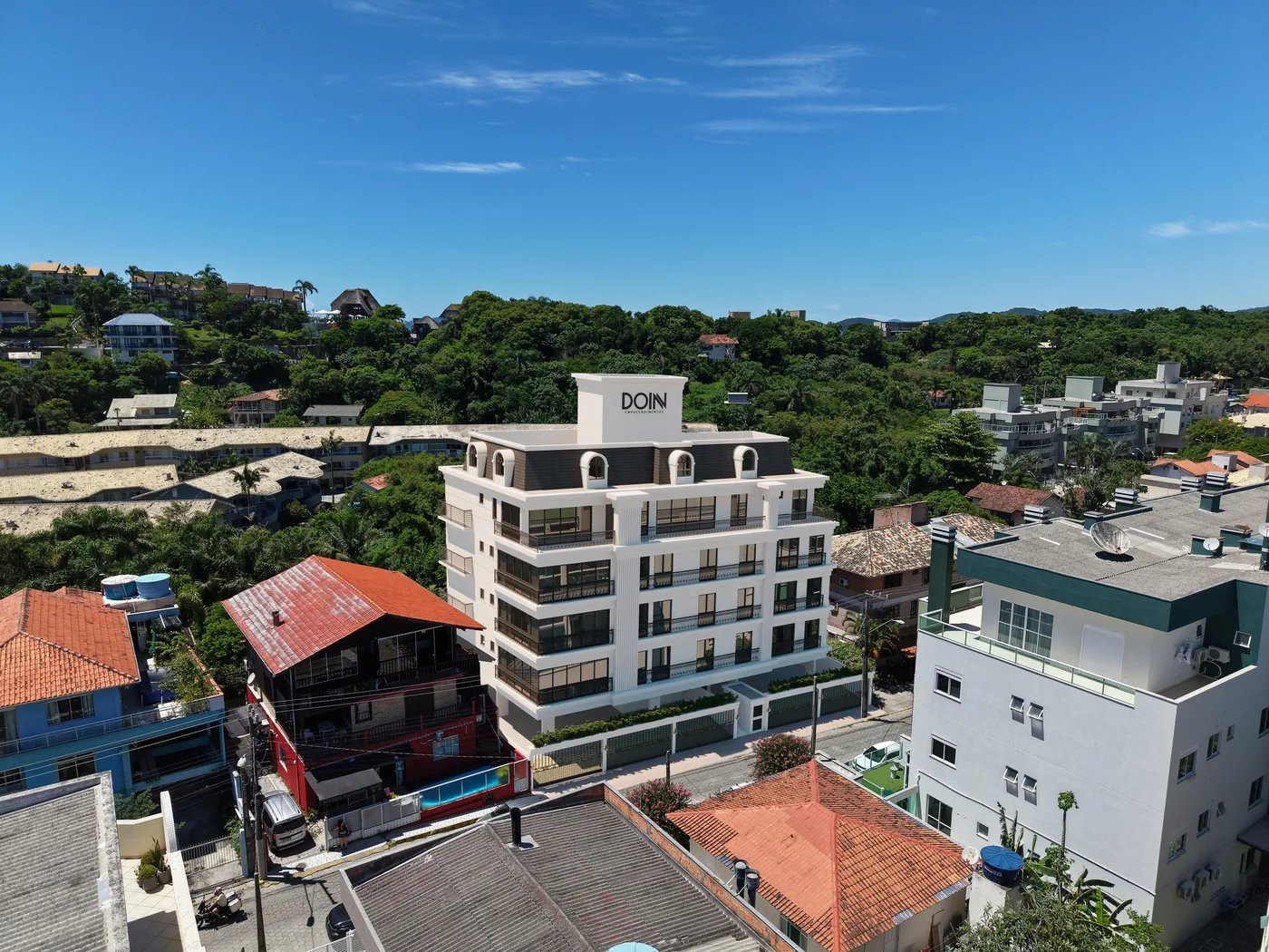 O Château de Lumière visto de cima entre as casas do Centro, com o morro coberto de mata logo atrás