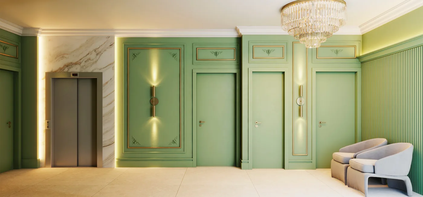 Hall de entrada com boiseries verdes, molduras douradas, lustre de cristal, mármore claro na parede do elevador e poltrona branca ao fundo
