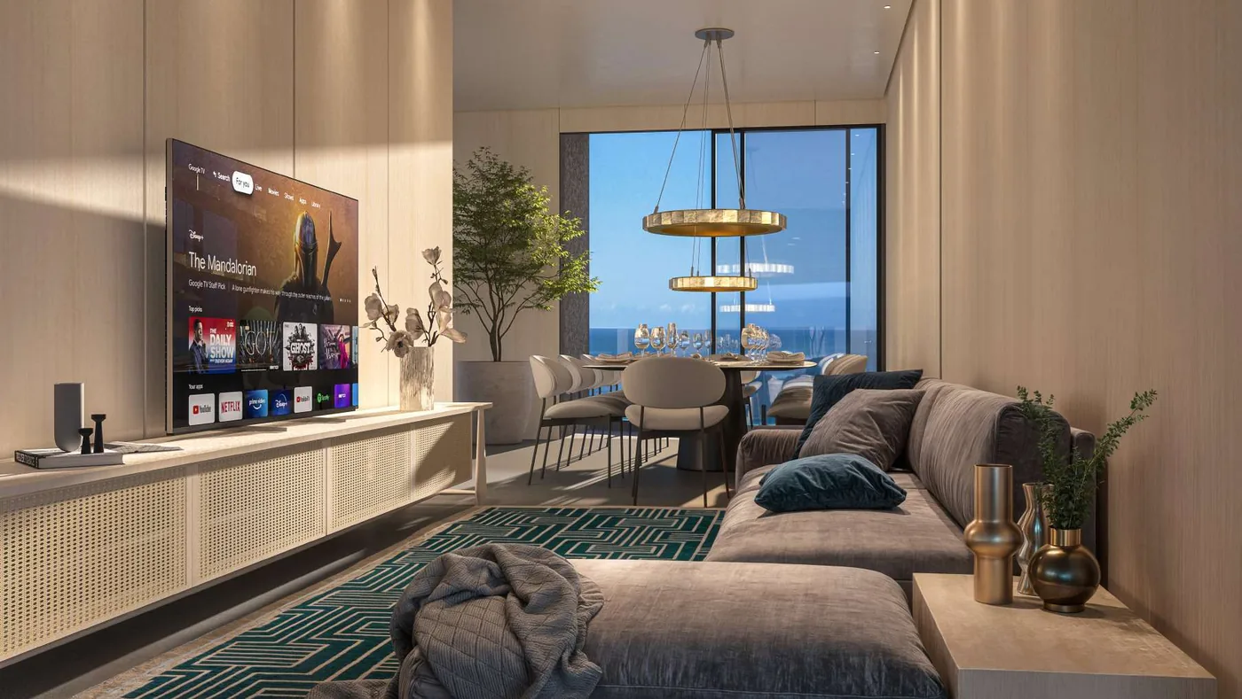Living da cobertura, com sofá modular claro, painel de TV suspenso, pendentes dourados e o jantar junto da janela