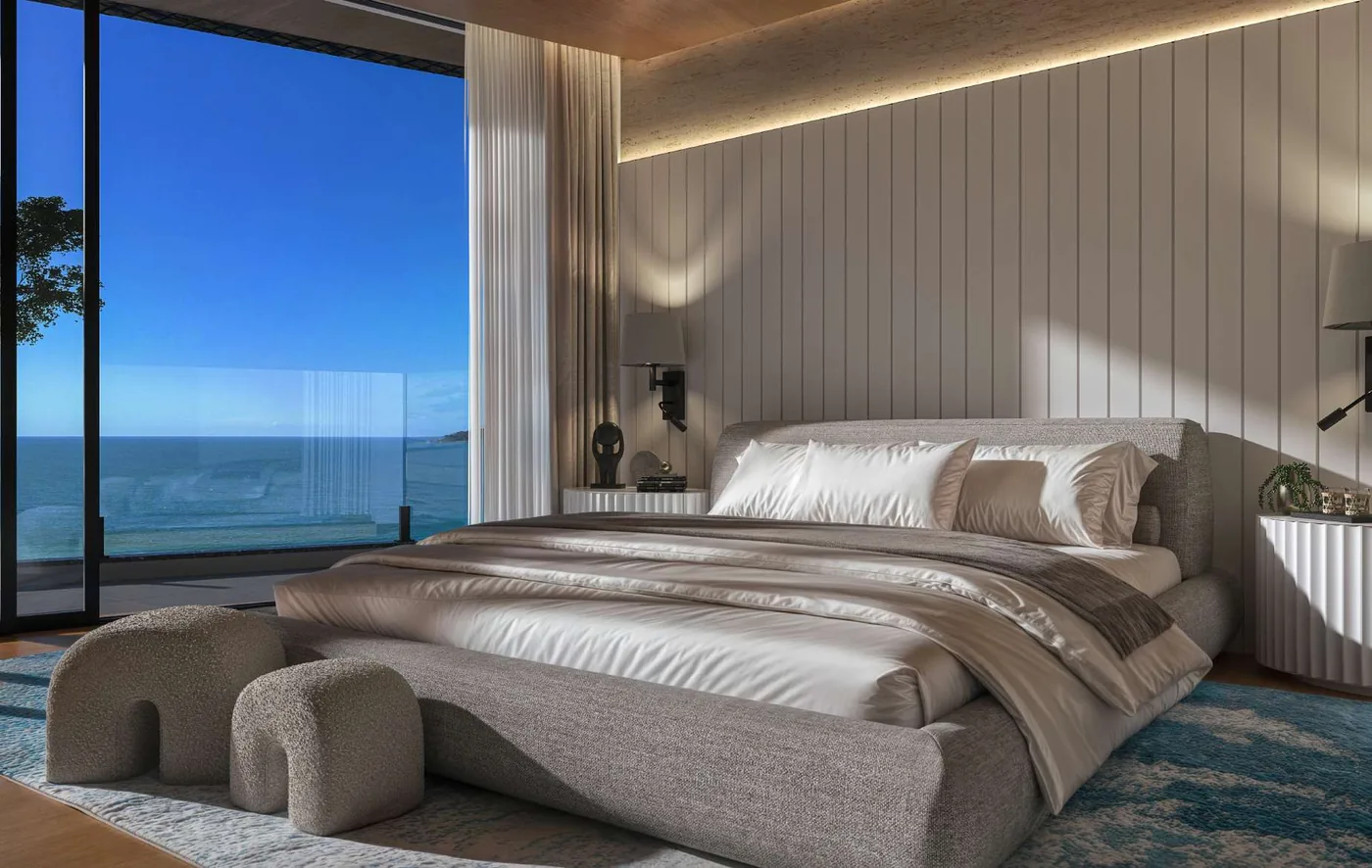 Suíte master da cobertura, com cama de frente para a janela de canto, banheira ao lado e o mar ocupando a vista inteira