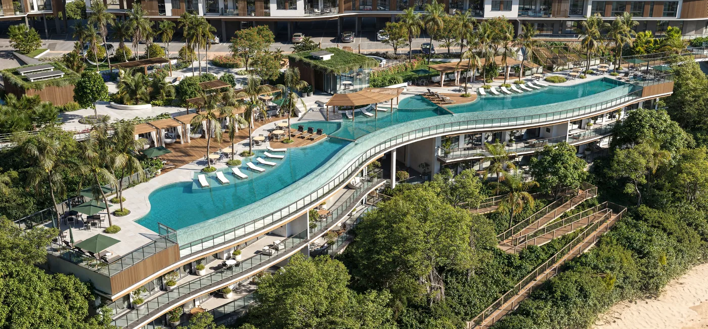 Vista aérea do conjunto do Porto Ribeiro Village: as torres escalonadas na encosta coberta de mata e a piscina alongada acompanhando o terreno