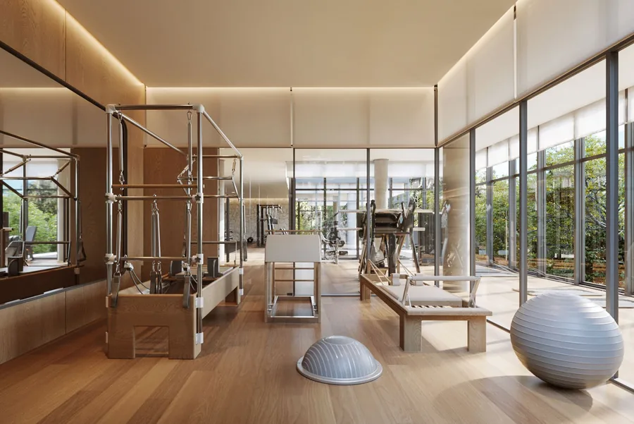 Espaço de pilates equipado com reformer e bolas, iluminado por janelas amplas