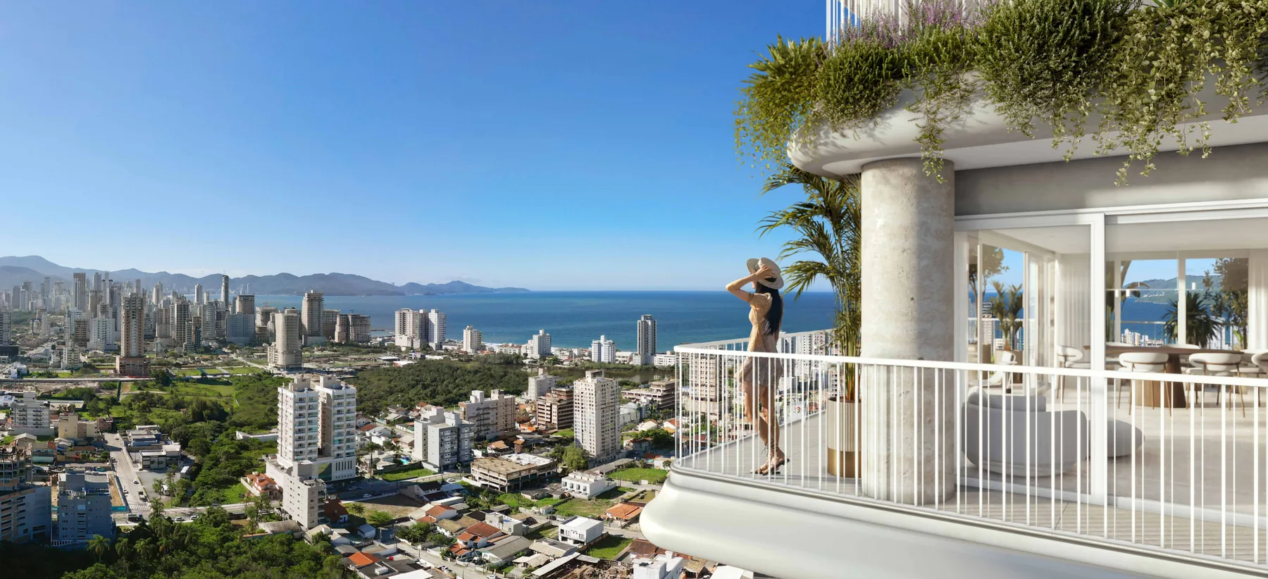 Sacada de apartamento do Velta em vista ampla, com churrasqueira ao fundo, guarda-corpo de vidro e a cidade e o mar à frente