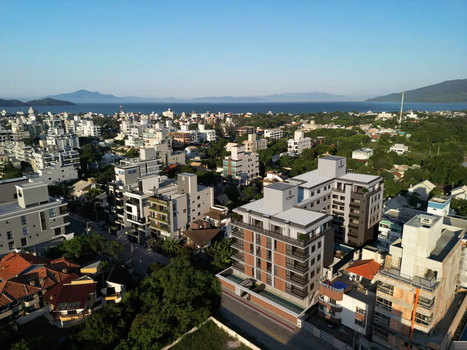 Vista aérea do bairro de Canto Grande com o prédio do Villa Amoreira entre as casas, a vegetação em volta e o morro ao fundo