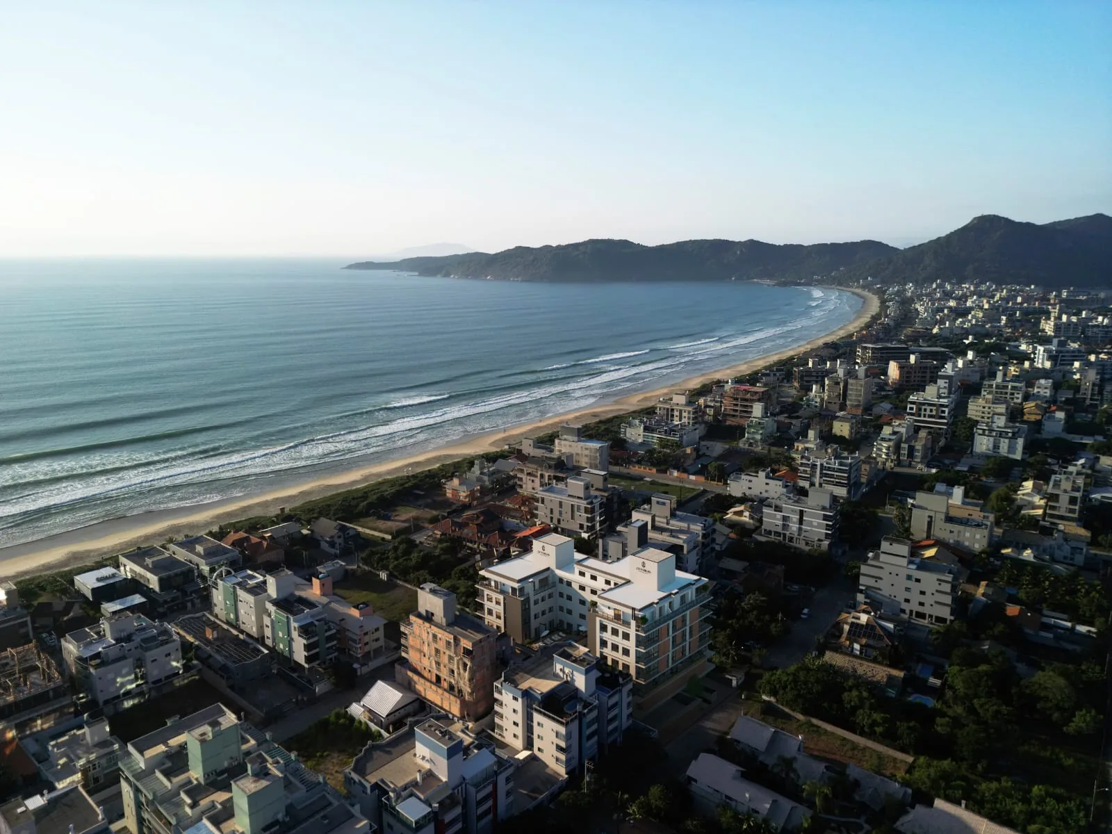 A praia de Canto Grande vista do alto em toda a sua extensão, com o mar aberto, a areia clara e o costão fechando a ponta