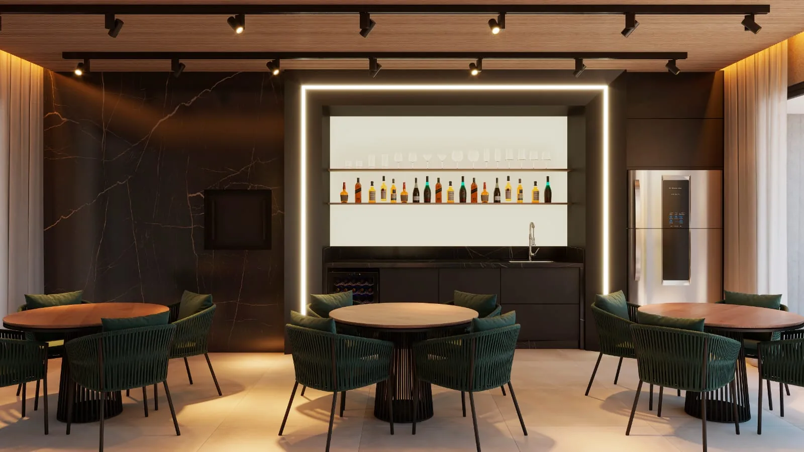 Espaço gourmet com bar iluminado e prateleira de garrafas ao fundo, mesas redondas e cadeiras verdes de palhinha