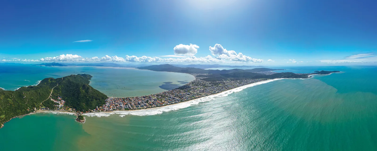 Vista aérea da enseada de Canto Grande, com a faixa de areia longa, o costão de mata ao fundo e o mar aberto