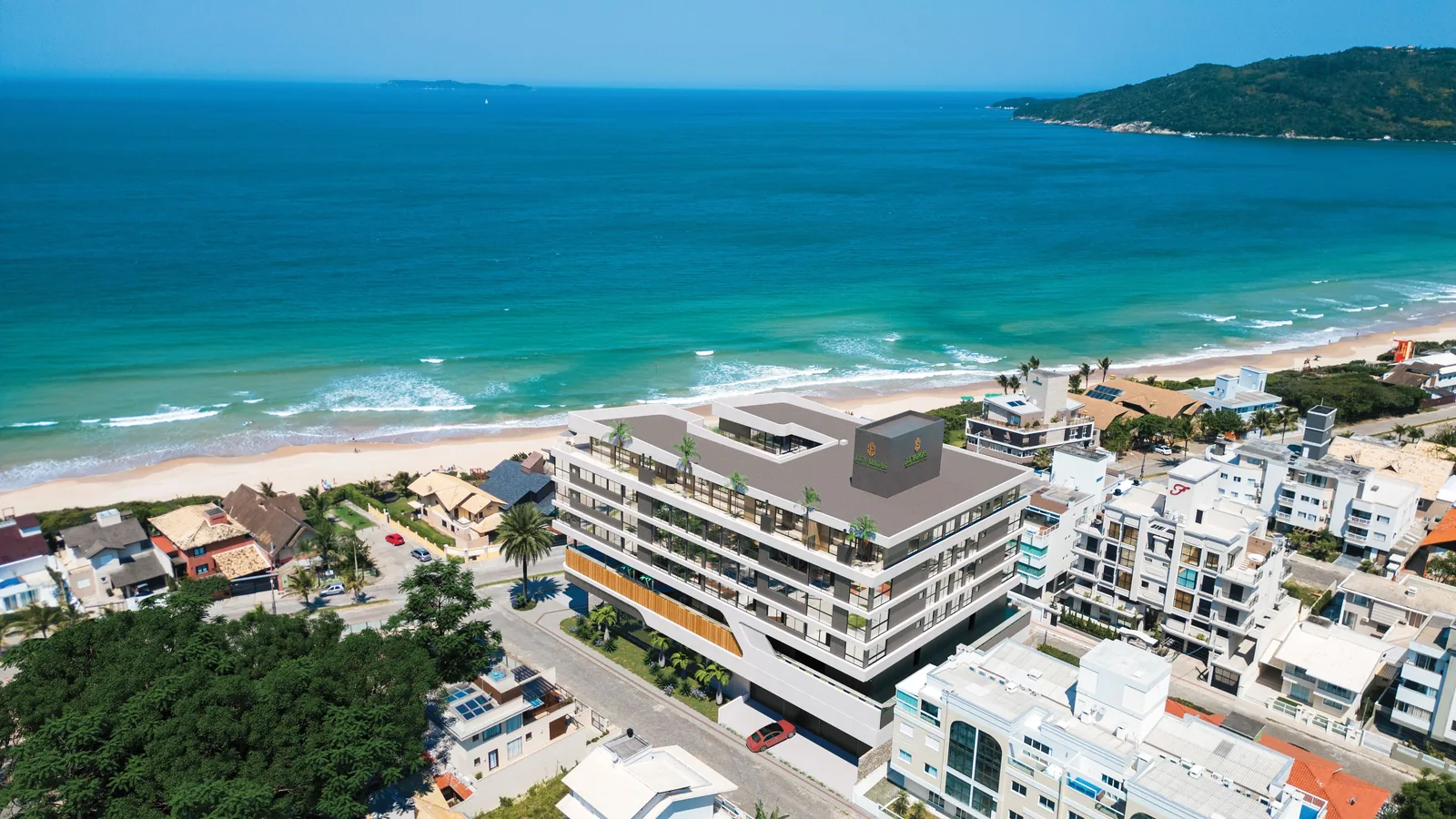 Vista aérea do bairro com o Villa Coral inserido entre as casas e prédios baixos, e a praia logo à frente