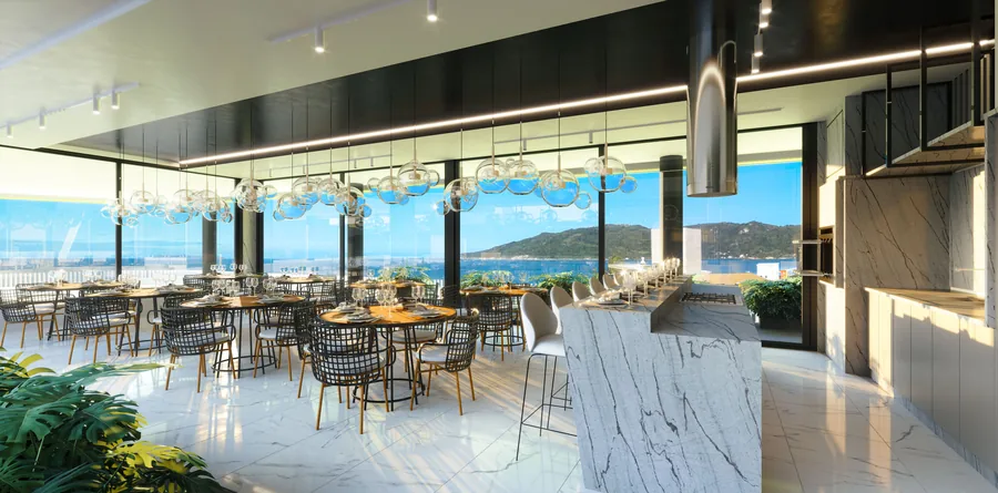 Espaço gastronômico com bancada de pedra clara, mesas altas e janelas abertas para o mar