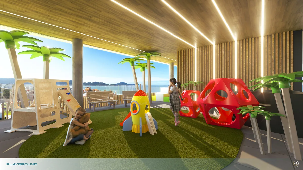 Playground coberto com grama sintética, brinquedos de escalada e palmeiras artificiais